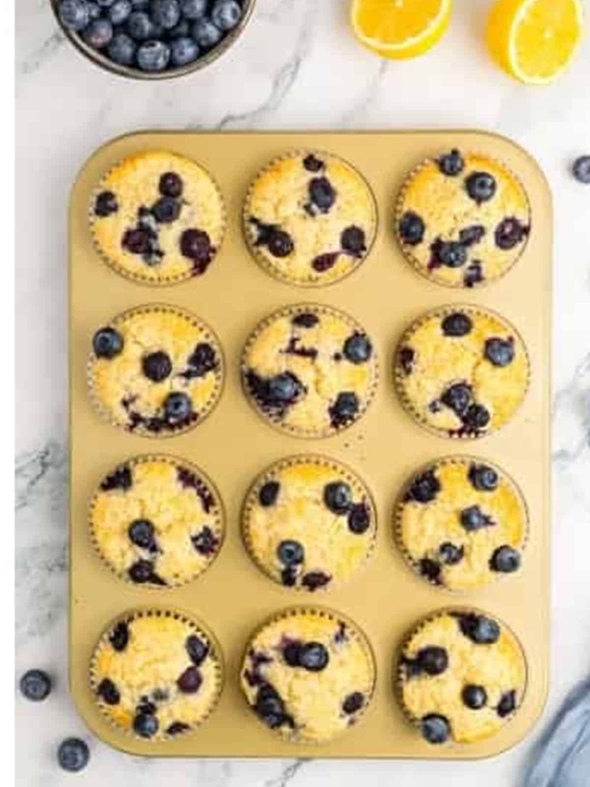 Golden baked lemon blueberry muffins in a muffin tin.