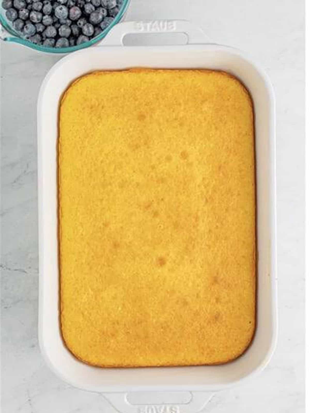 A baked lemon cake cooling in a 9x13 baking dish.