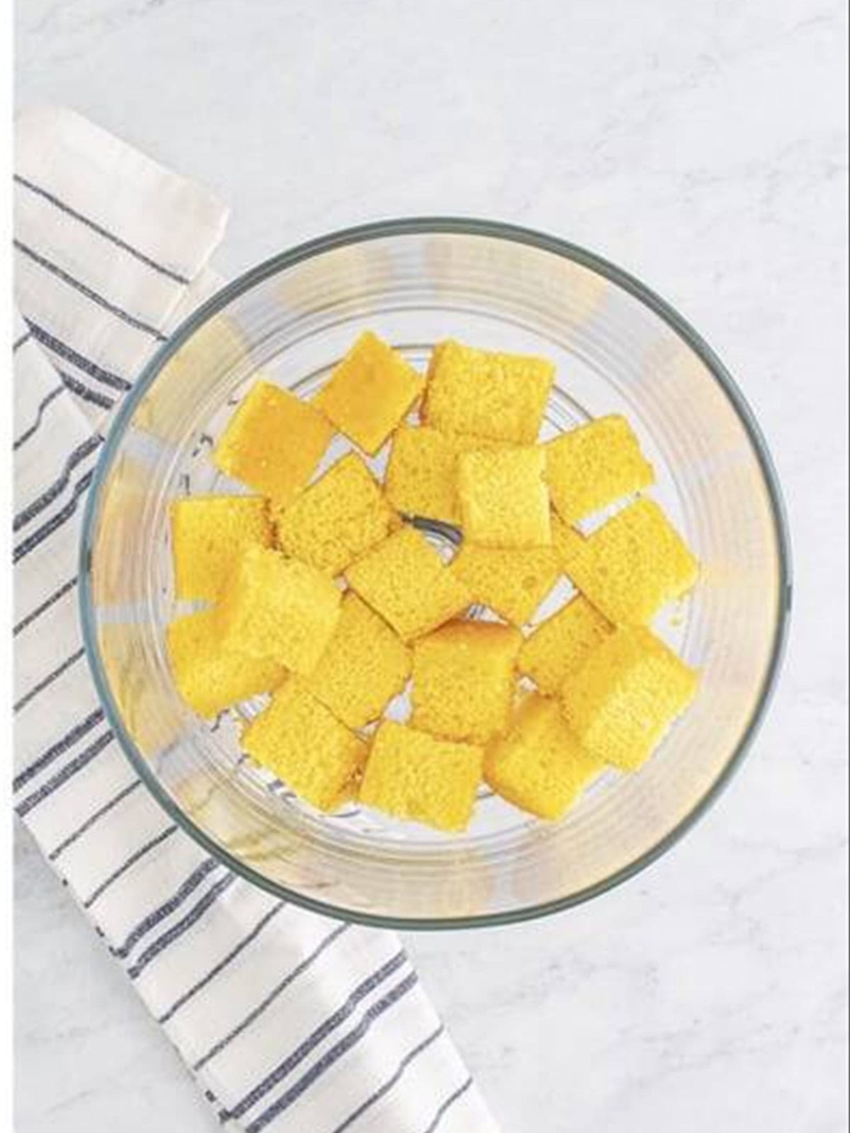 Lemon cake cubes layered in the bottom of a trifle dish.