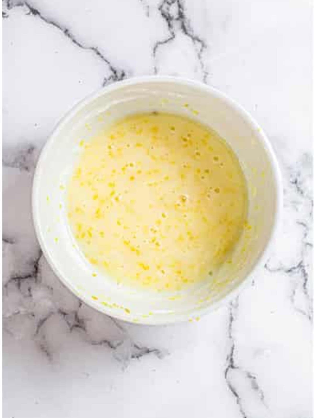 Whisking oil, sugar, eggs, and milk together for lemon bread batter.