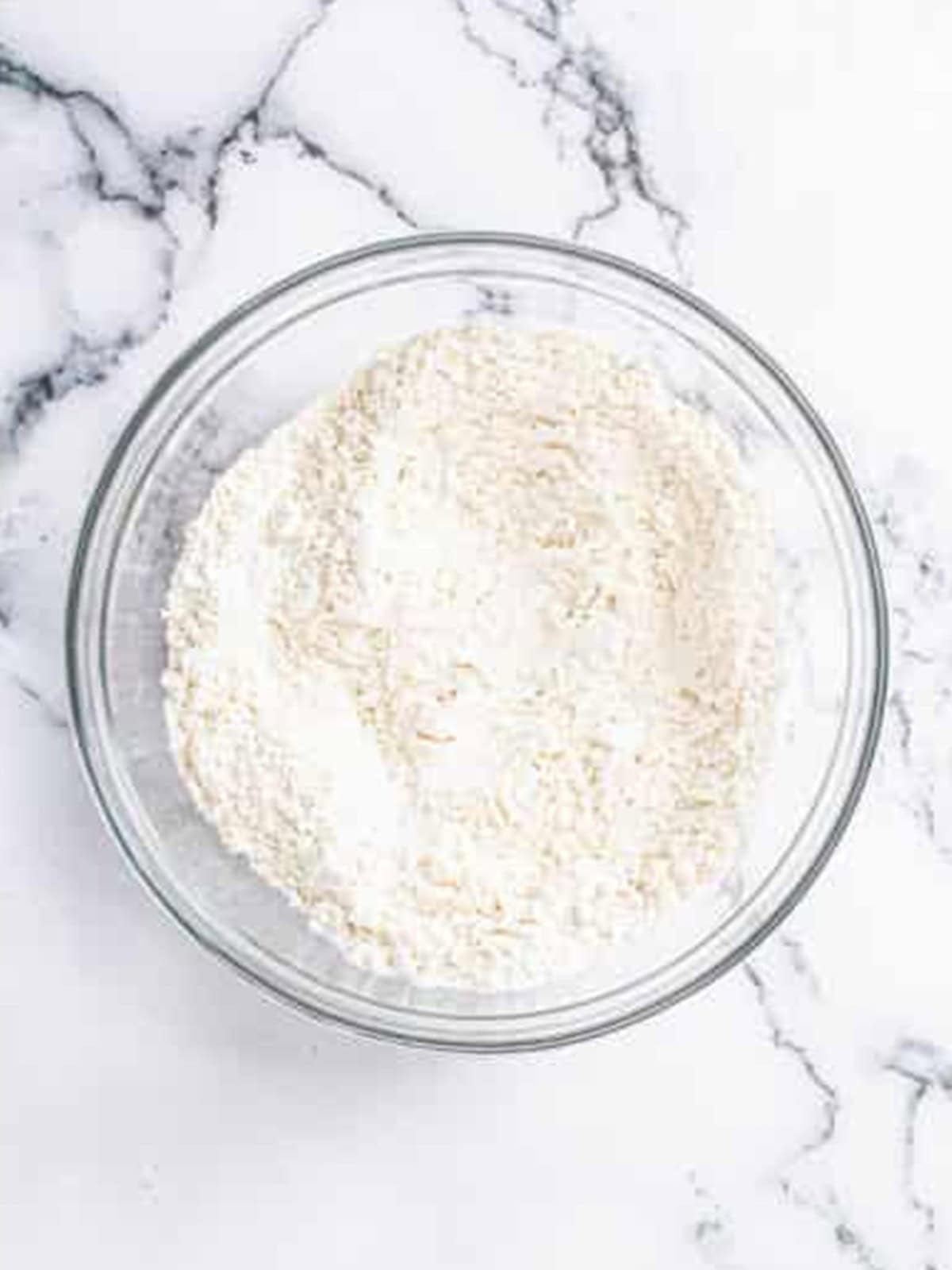 Combining the dry ingredients for lemon bread in a glass bowl.