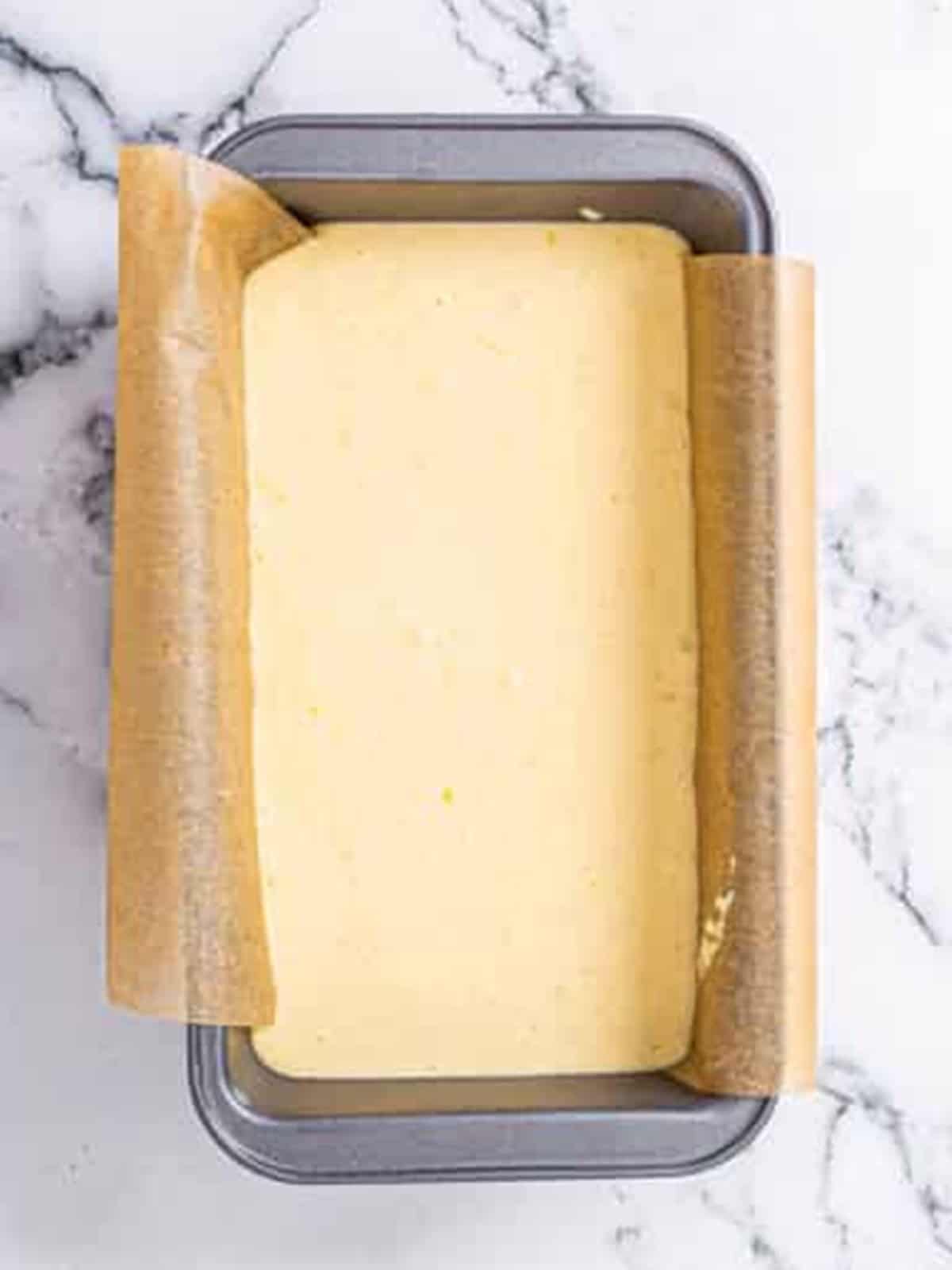 Lemon bread batter poured into a parchment-lined loaf pan.