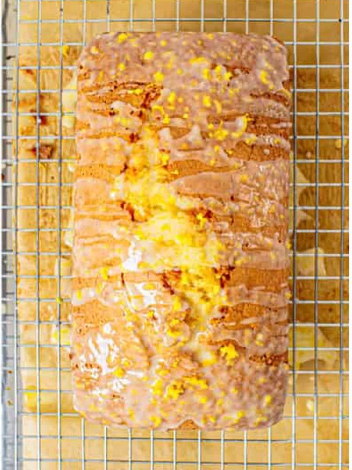 Baked lemon bread drizzled with lemon glaze on a cooling rack.