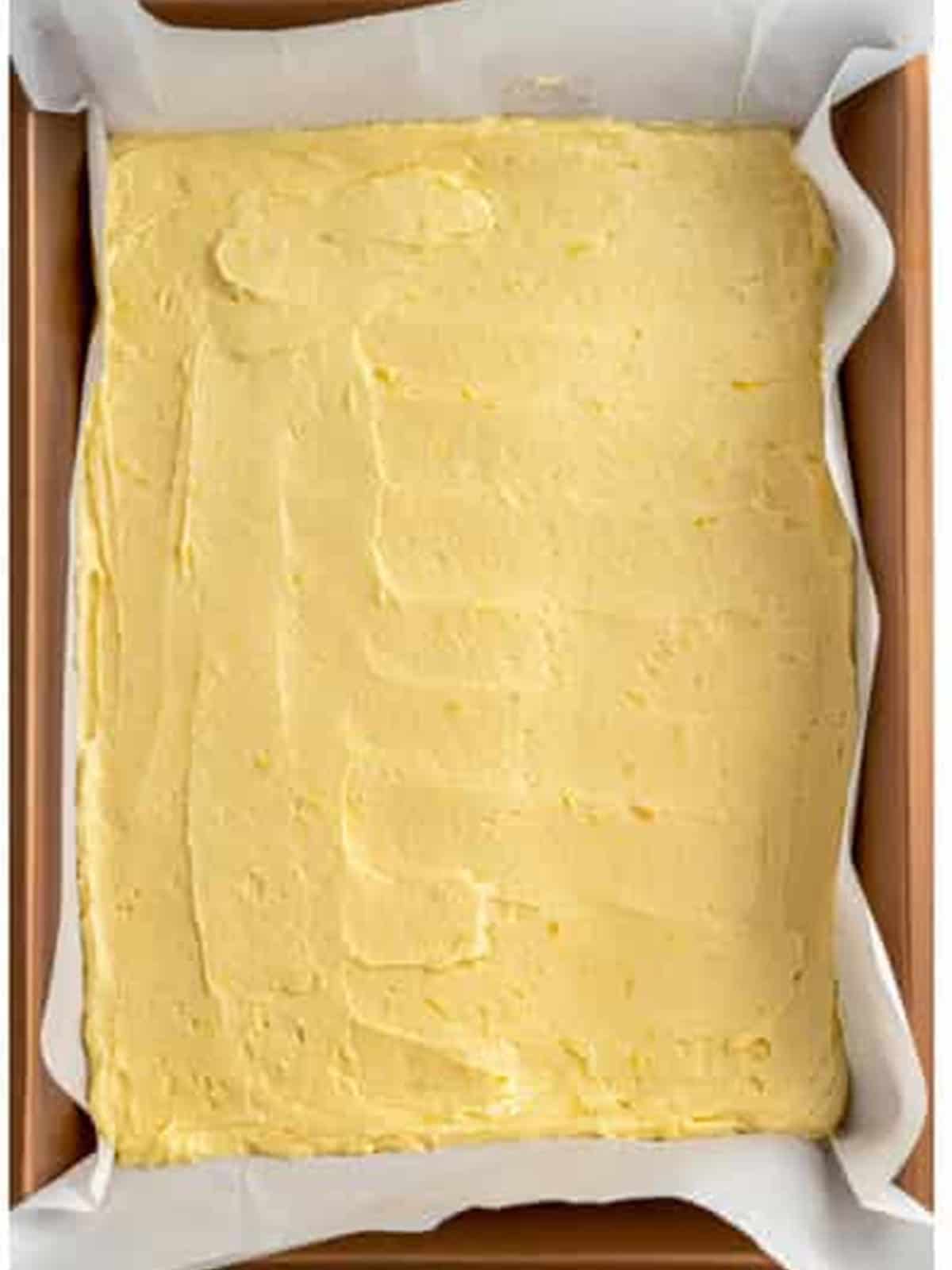 Lemon brownie batter spread evenly in a parchment-lined pan.
