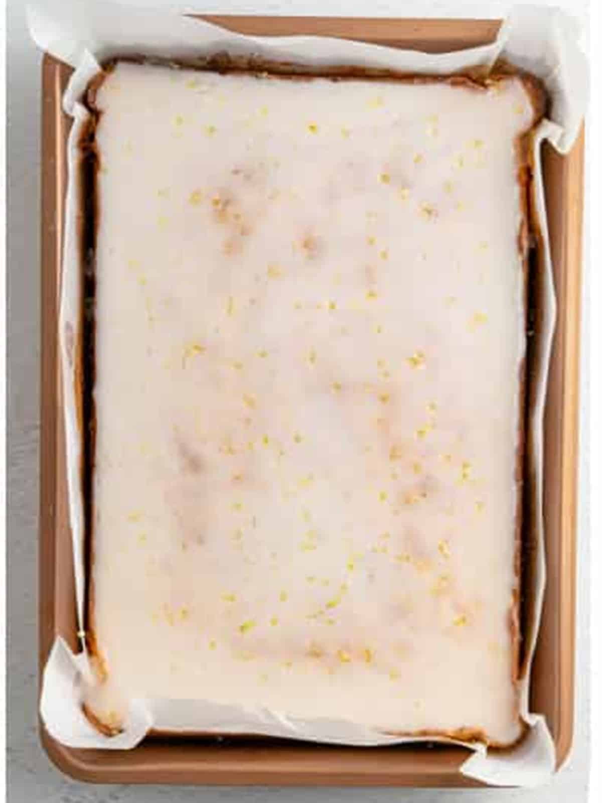 Lemon brownies coated in a fresh lemon glaze in the pan.