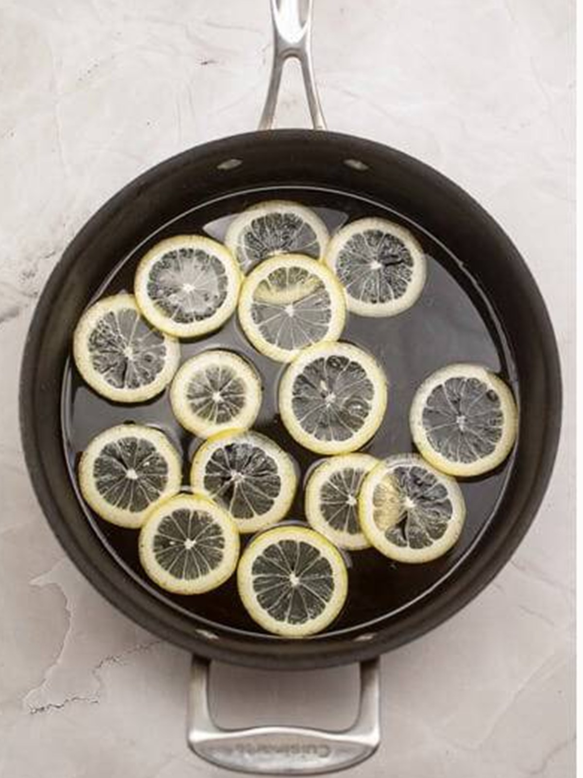 Candied lemon slices simmering in sugar syrup in a pan.