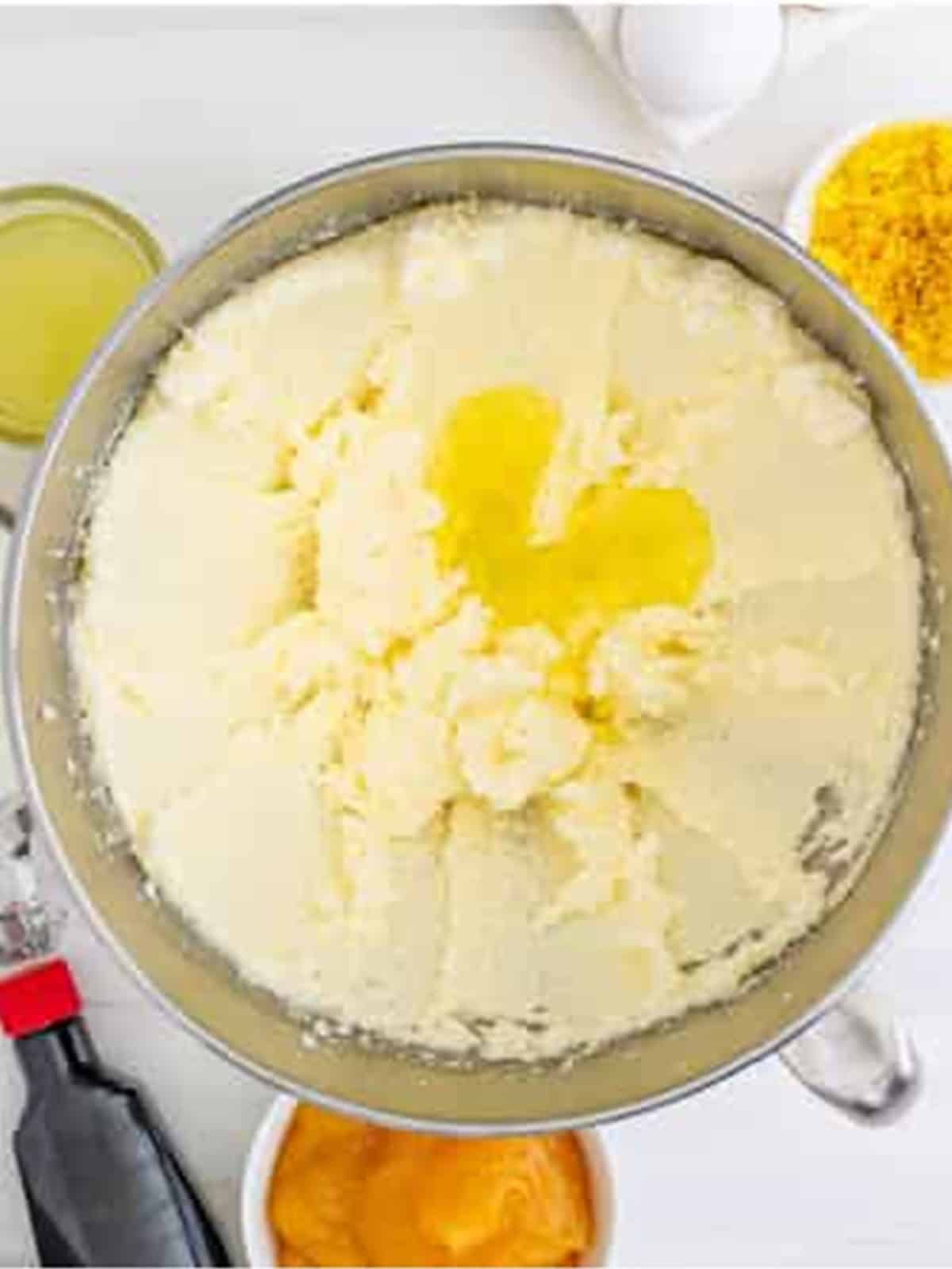 Lemon cake batter being mixed with egg whites in a stand mixer bowl.