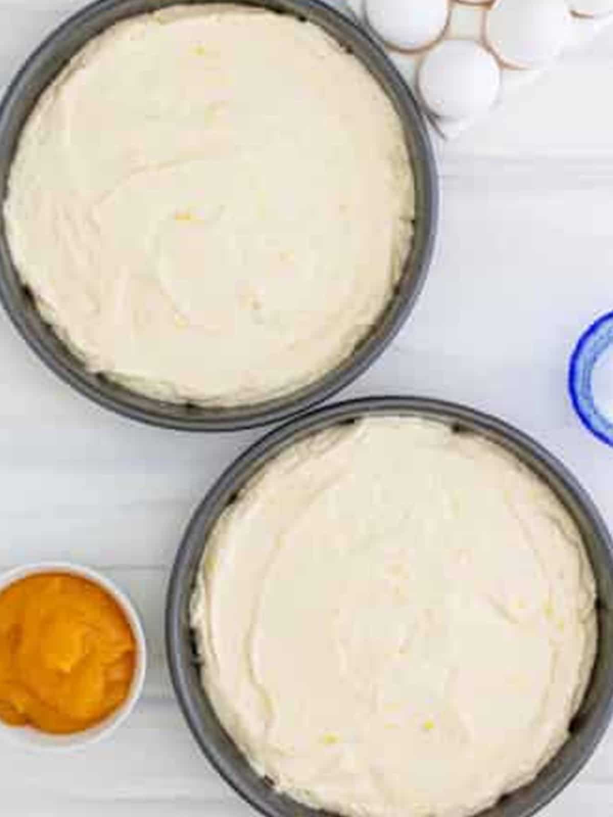 Lemon cake batter divided between two round cake pans.