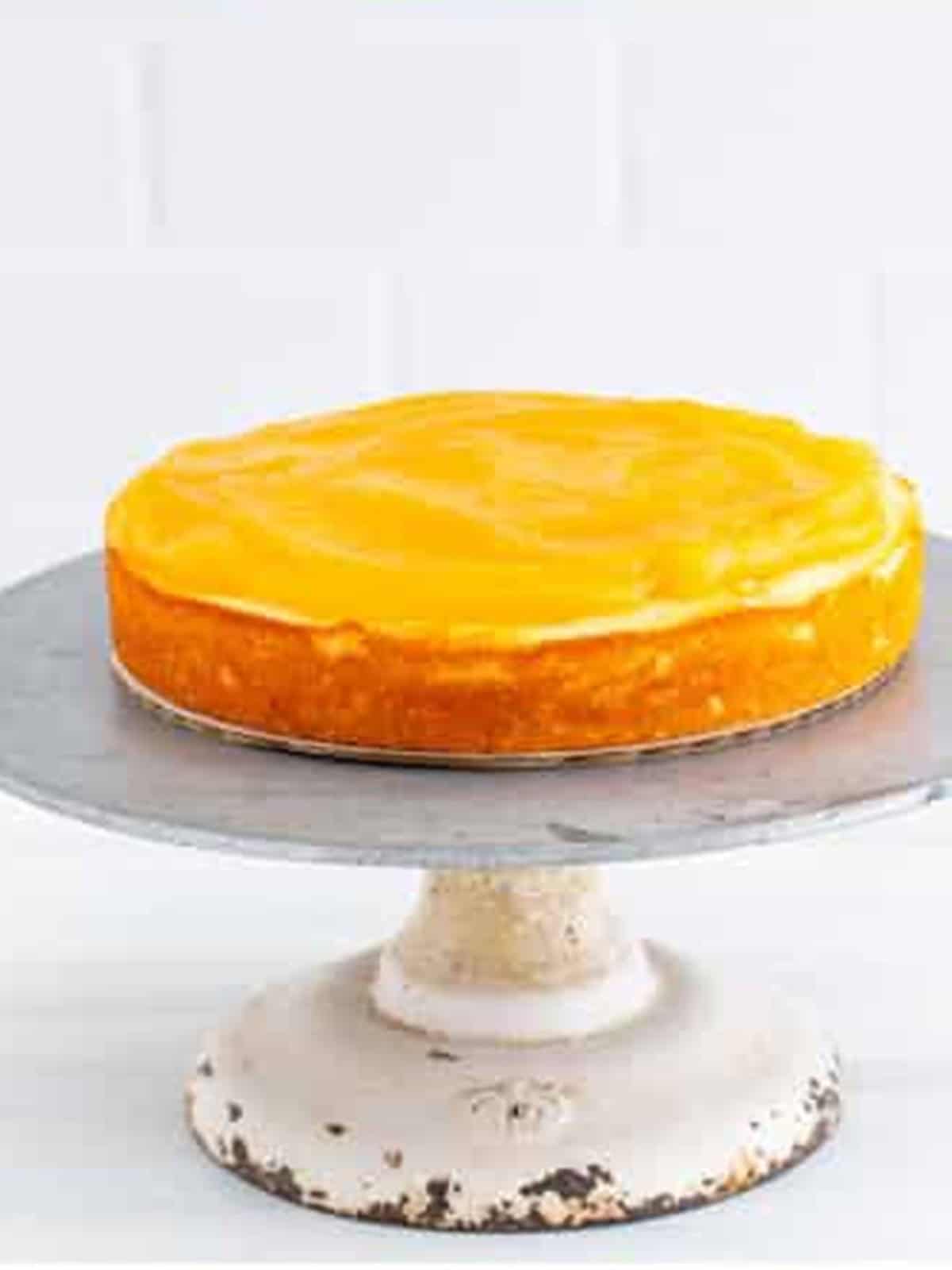 Lemon curd spread over the first layer of lemon cake on a cake stand.