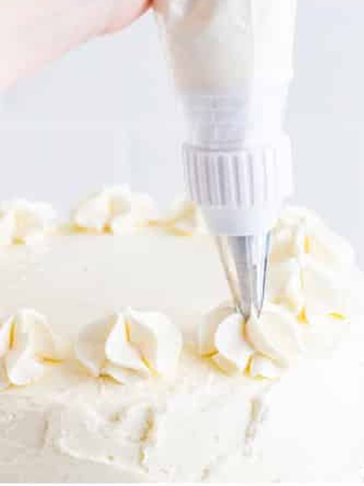 Lemon buttercream being piped onto the assembled lemon cake.
