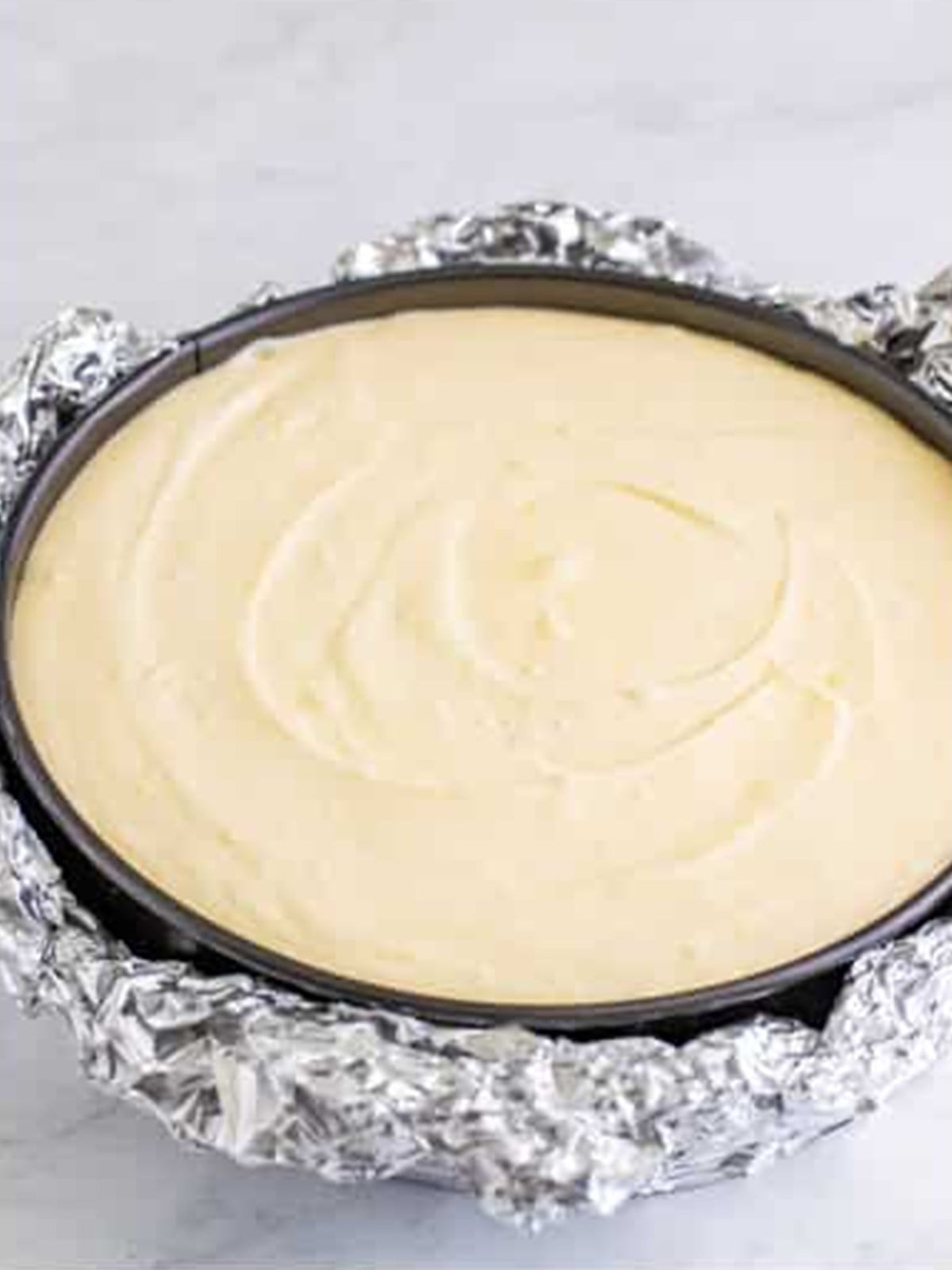 Pouring the Lemon Cheesecake filling into the foil wrapped pan for a water bath.