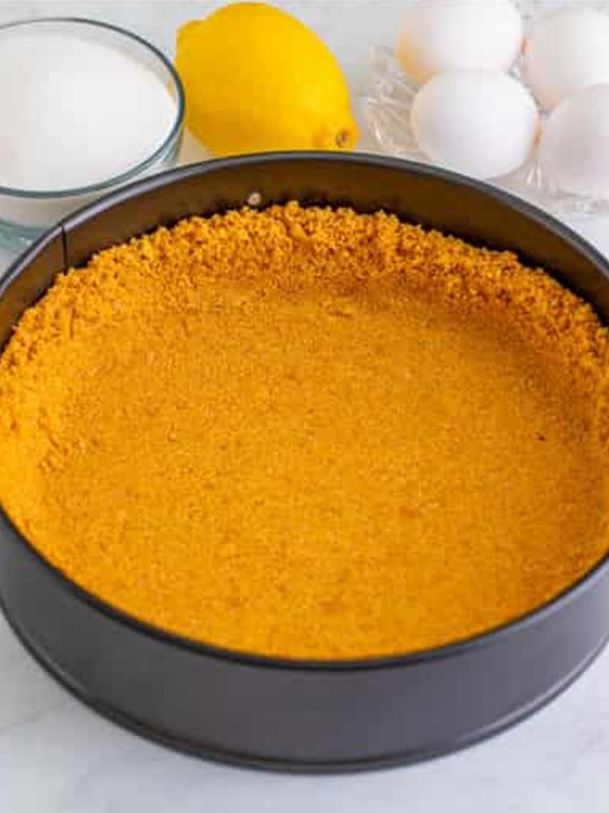 Pressing the graham cracker crust into a springform pan.