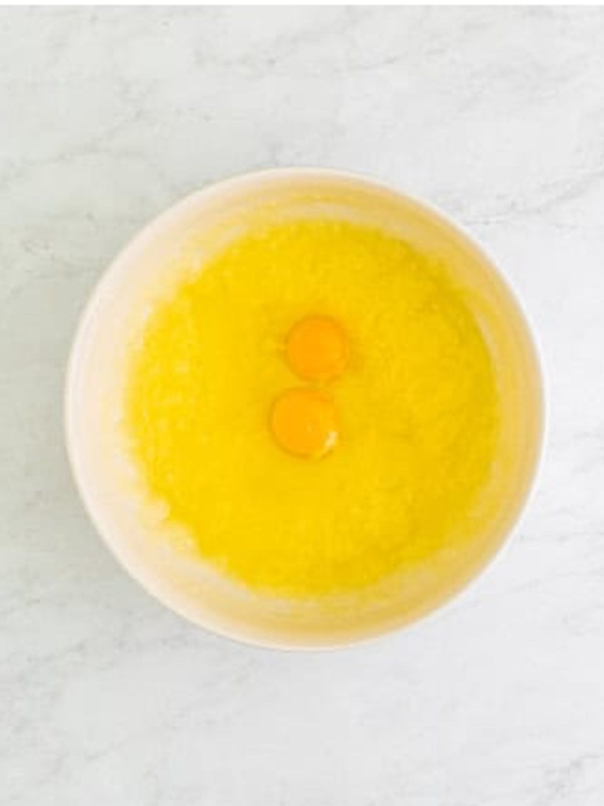 Adding eggs to the wet ingredients for lemon cupcakes.