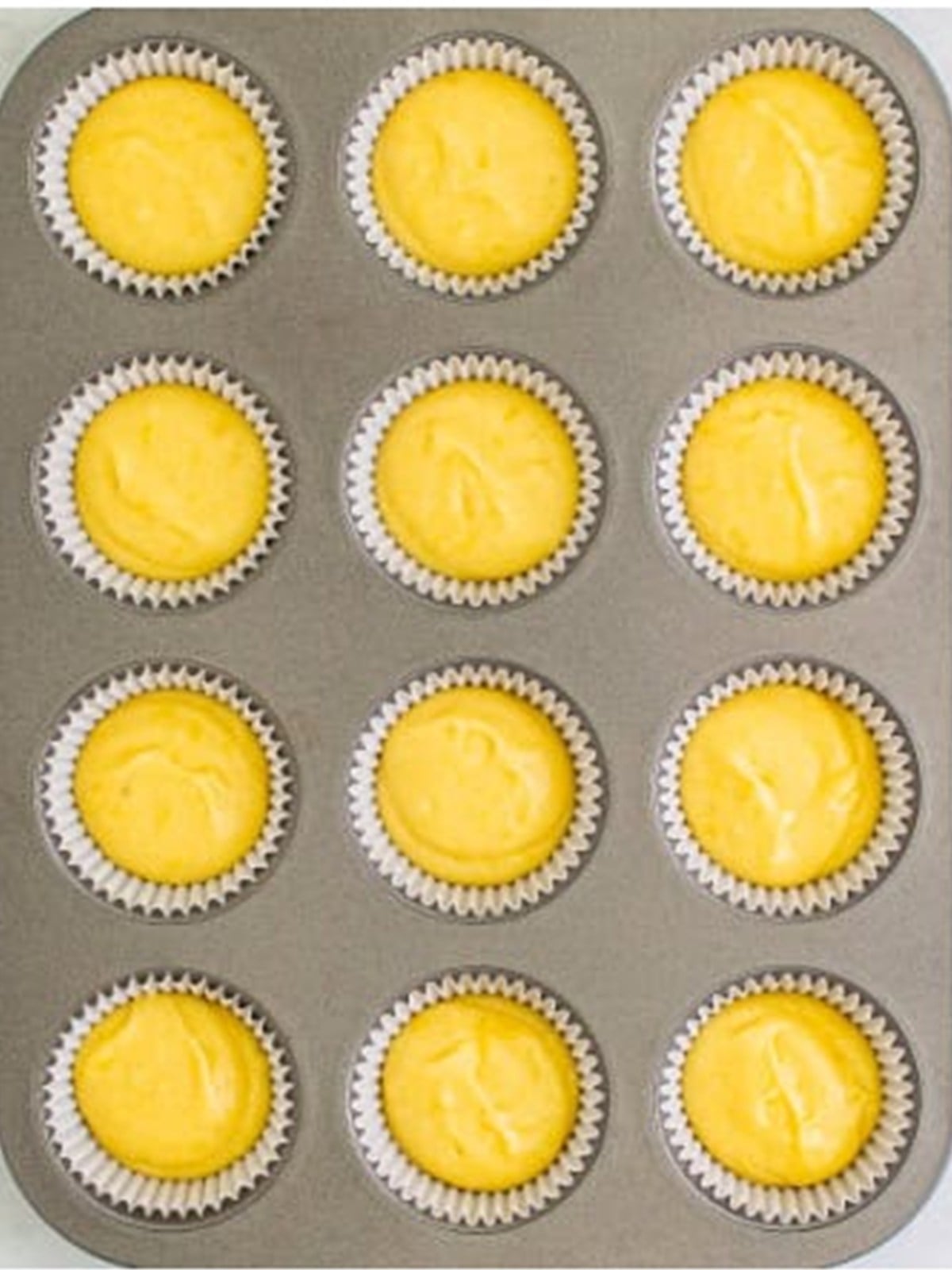 Lemon cupcake batter divided into a lined cupcake tin.