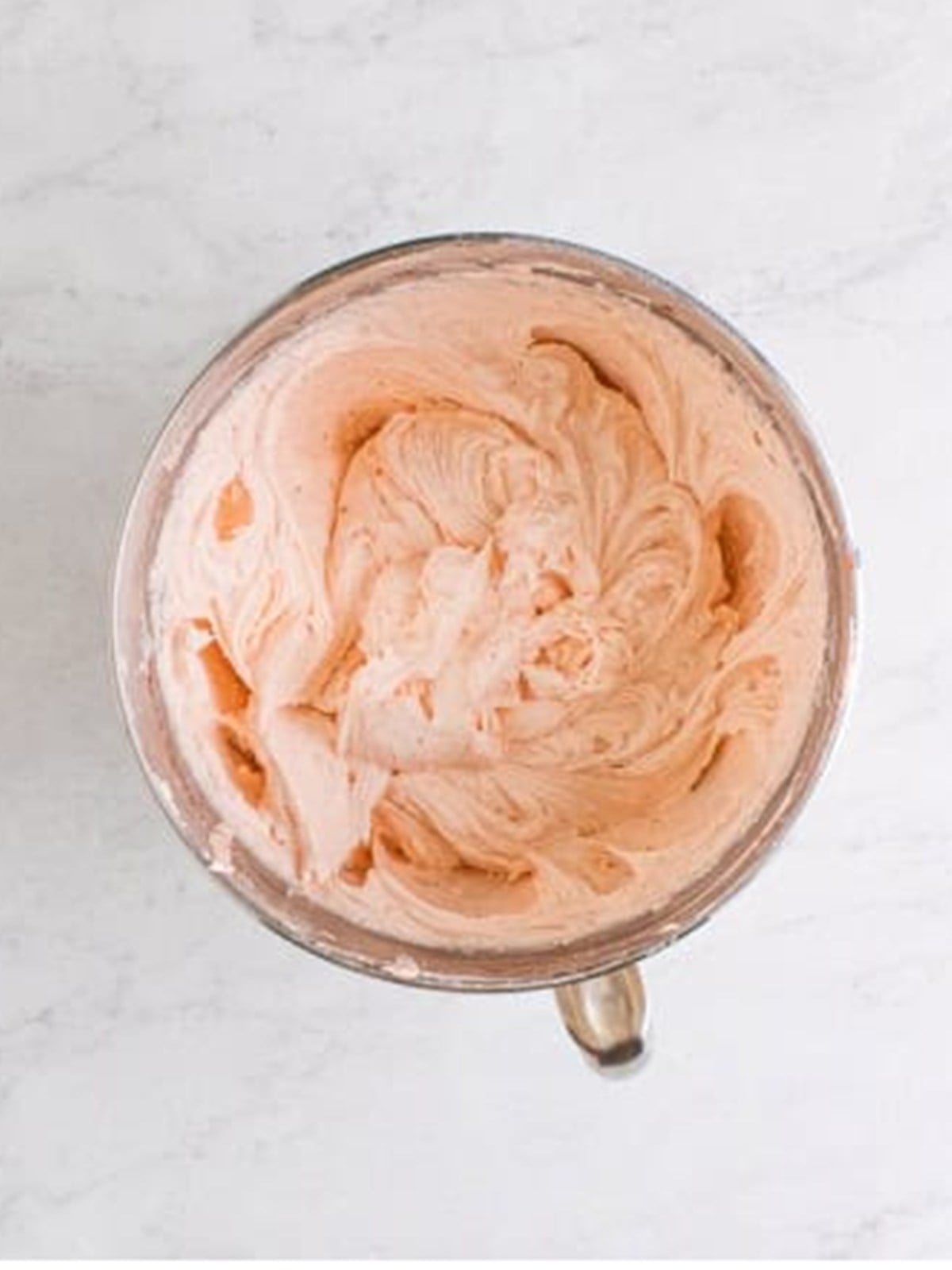 Whipped strawberry buttercream frosting in a mixing bowl.