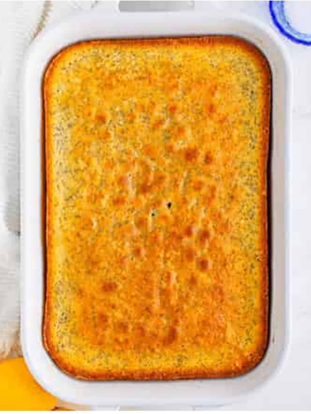 Baked golden lemon poppy seed cake in a baking dish.