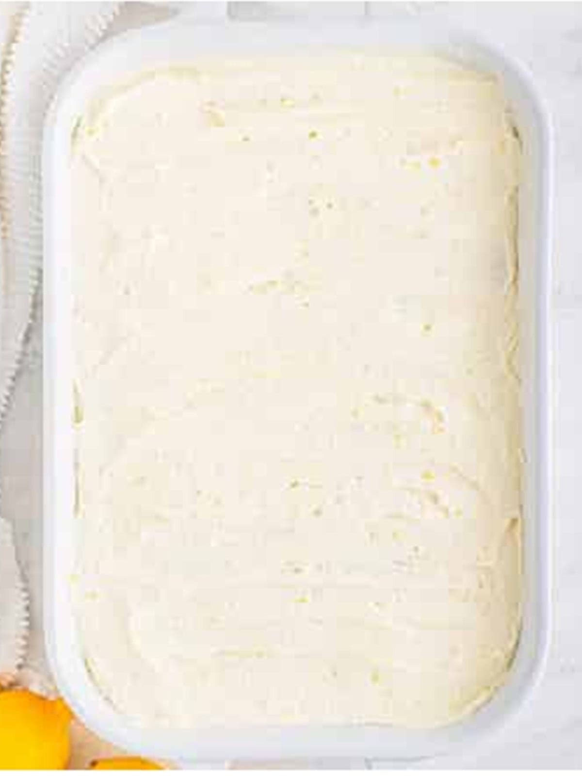 Lemon buttercream frosting spread over the cooled cake.