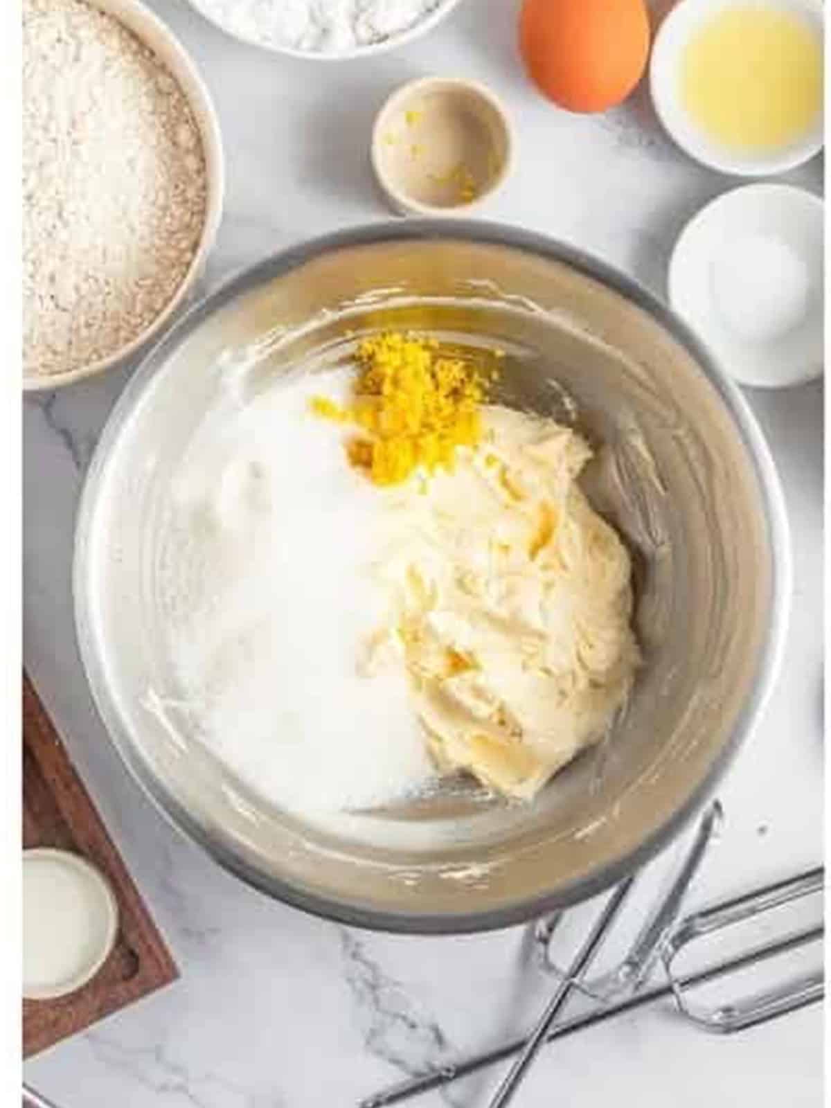Creaming butter with sugar and lemon zest in a mixing bowl for lemon sandwich cookies.