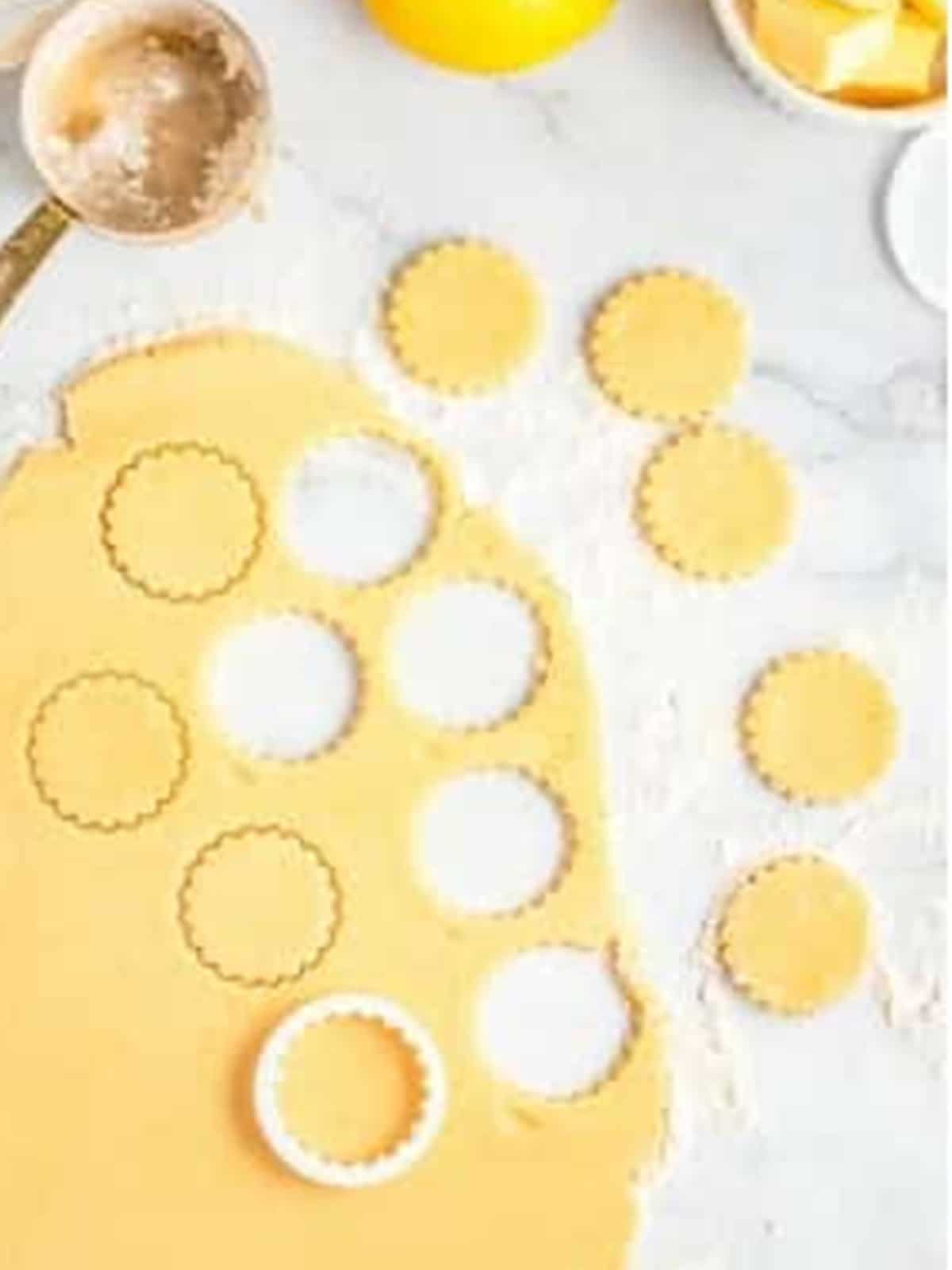 Lemon cookie dough rolled out and cut into round shapes.