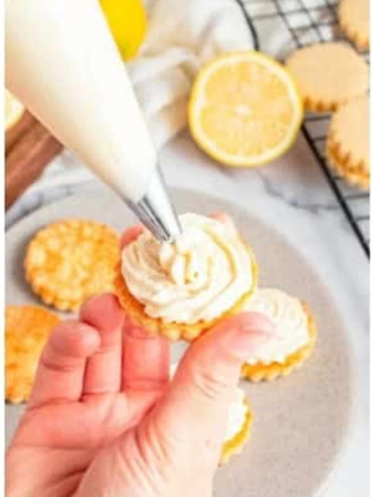 Piping lemon cream filling onto a baked cookie to make a sandwich.