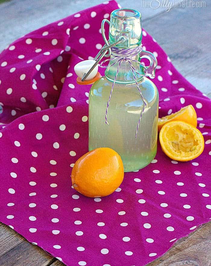 A bottle of homemade lemon simple syrup with fresh Meyer lemons.