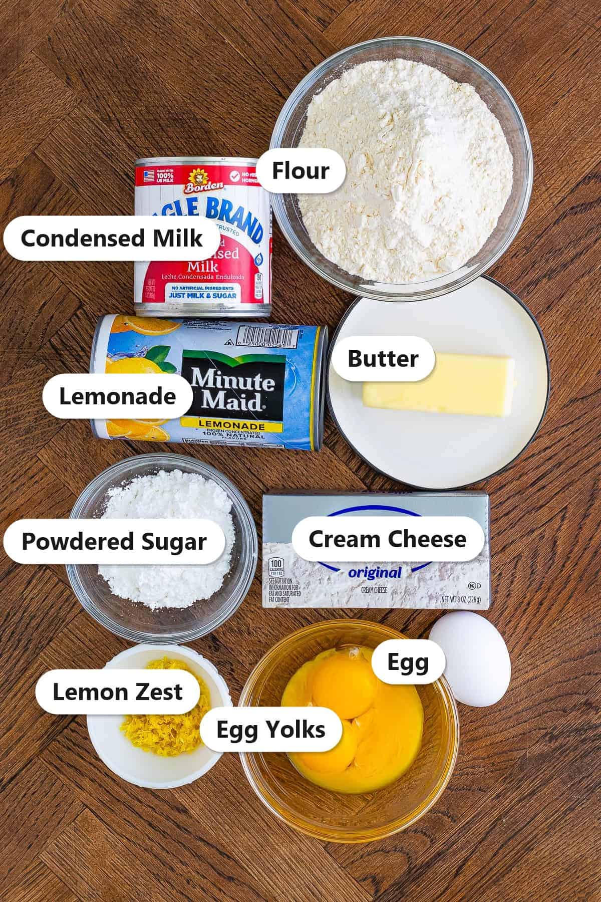 Labeled ingredients for lemonade tart including flour, butter, cream cheese, condensed milk, lemonade concentrate, and lemon zest.