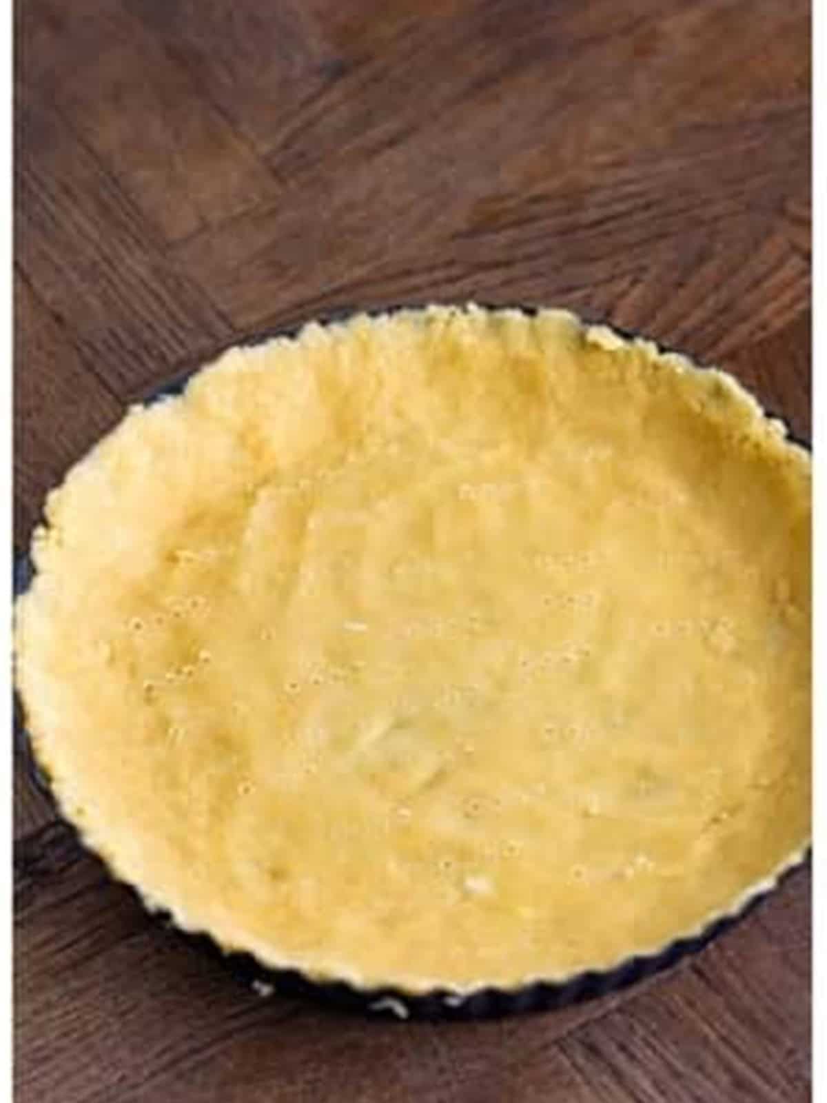 Tart crust dough pressed into the bottom and up the sides of a tart pan.