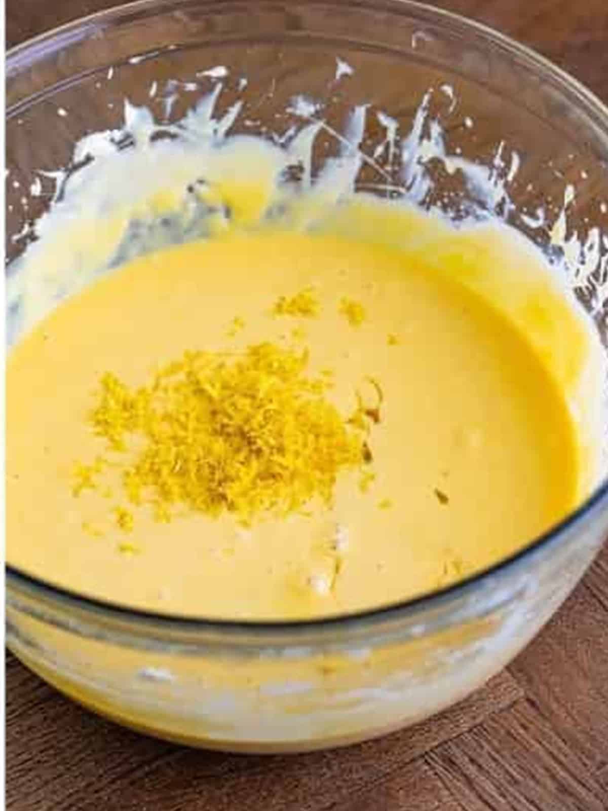 Creamy lemonade tart filling with lemon zest whisked in a bowl.