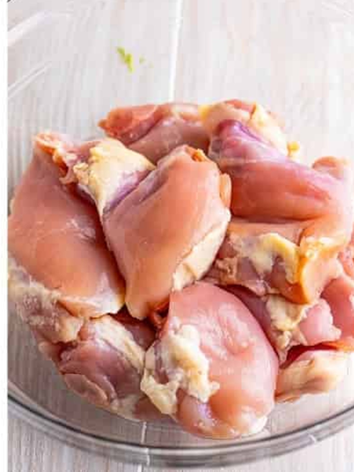 Boneless chicken thighs in a bowl ready to marinate for lemongrass chicken.