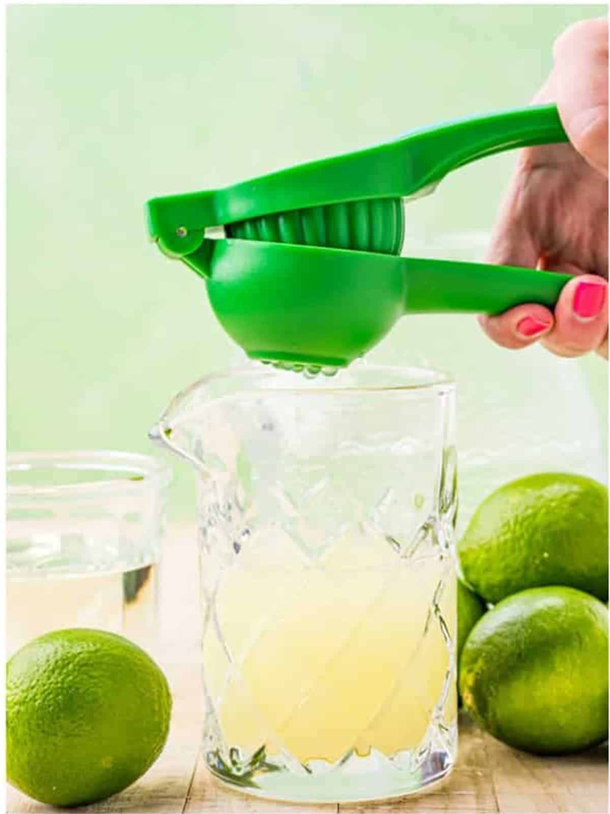 Fresh limes being juiced with a handheld juicer for limeade.