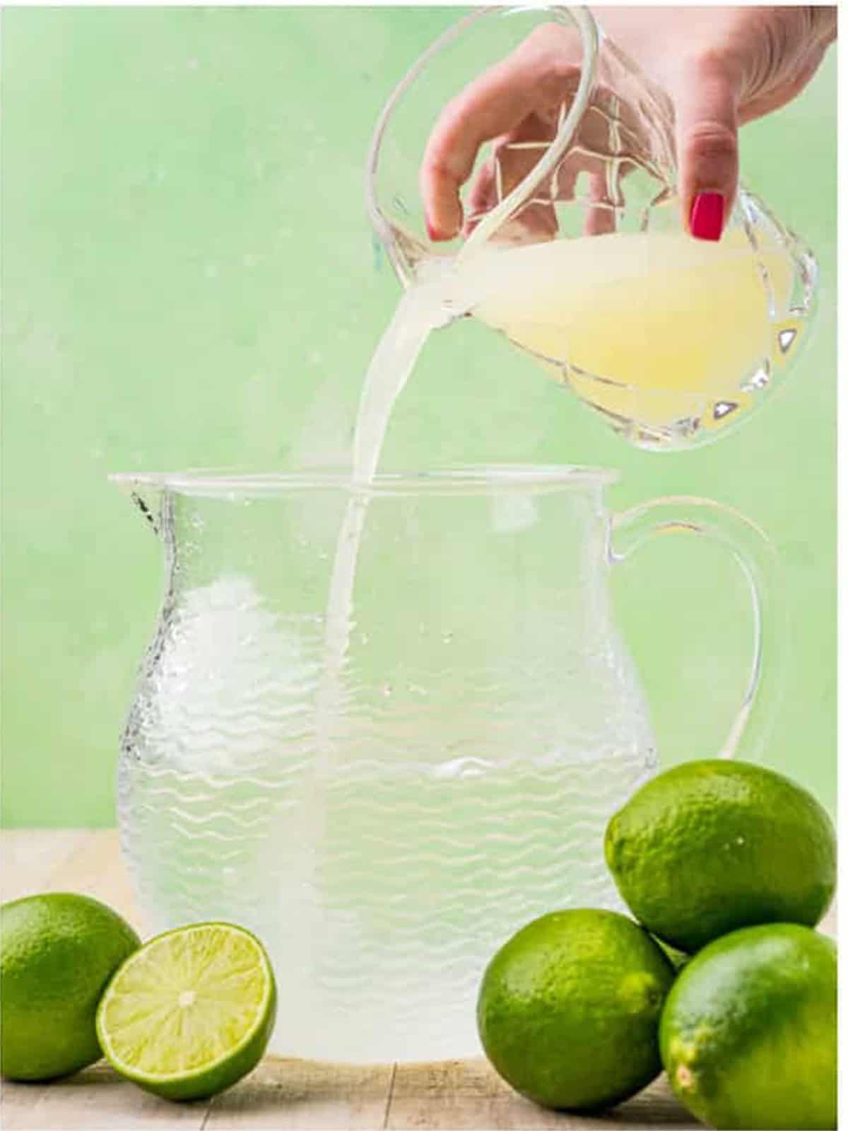 Fresh lime juice and simple syrup poured into a pitcher of water for limeade.