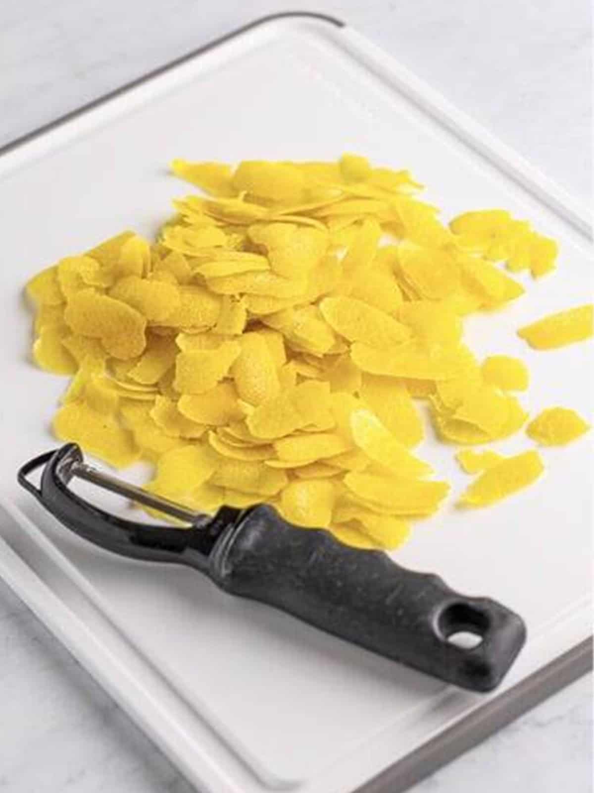 Peeling organic lemons with a potato peeler for limoncello recipe.
