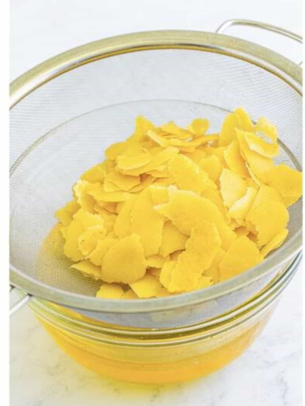 Straining lemon peels through a fine mesh strainer for limoncello recipe.