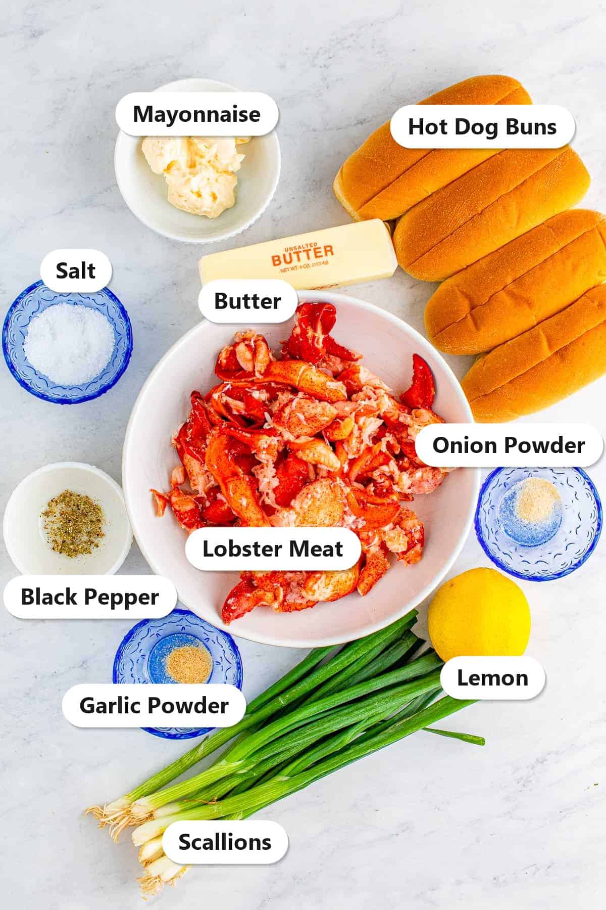 Labeled ingredients for lobster rolls including cooked lobster meat, mayonnaise, butter, scallions, lemon, and split top hot dog buns.