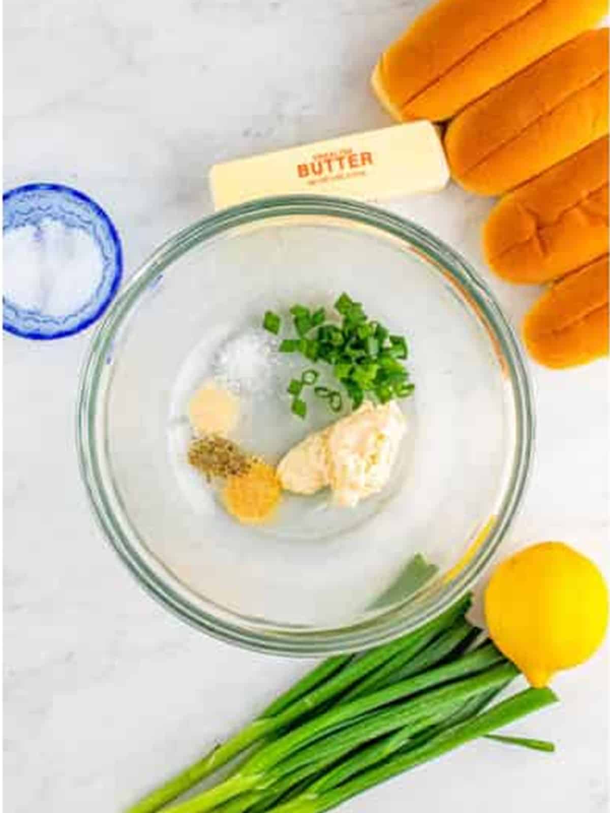 Mayonnaise, scallions, and seasonings combined in a glass bowl for lobster roll dressing.