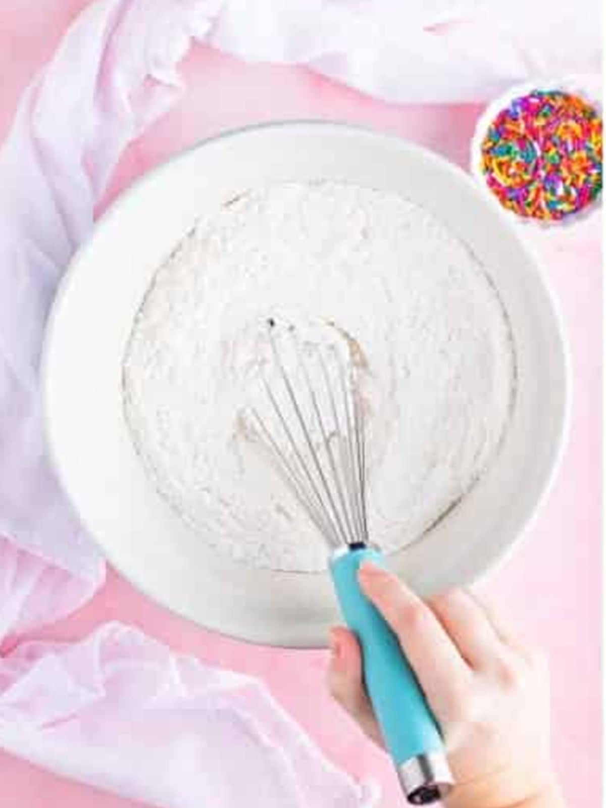 Whisking together cake flour and leaveners for lofthouse cookies in a white bowl.