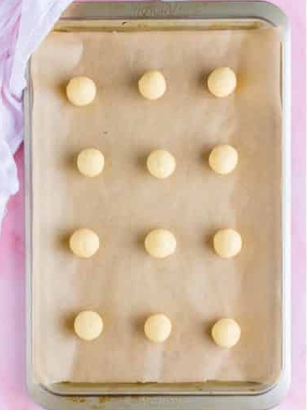 Scooped dollops of chilled lofthouse cookie dough on a parchment lined tray.