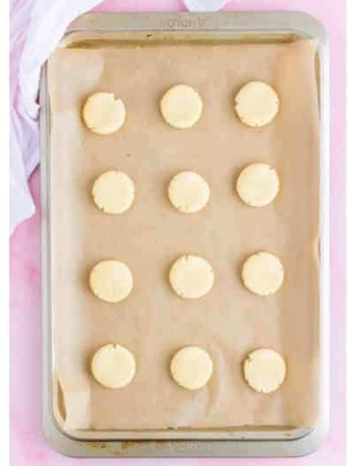 Lofthouse cookie dough balls gently flattened on the baking sheet.