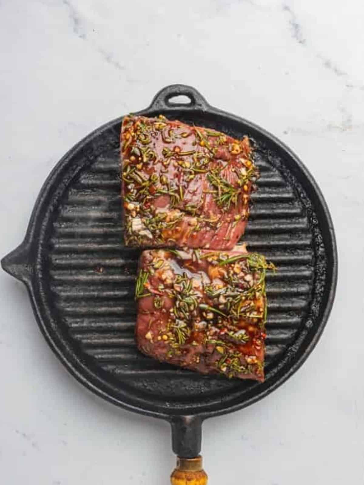 Marinated London broil cooking on a hot grill pan.