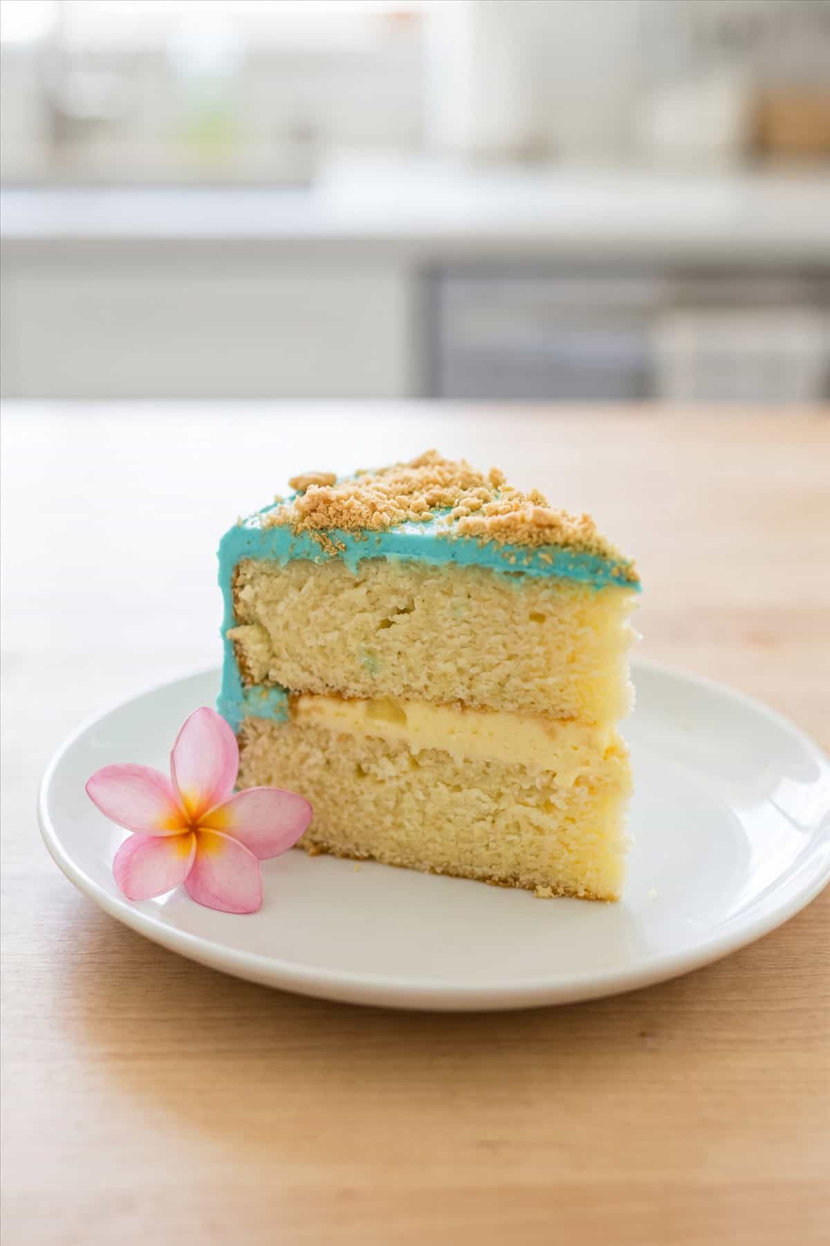 A slice of pineapple luau cake showing the layers and blue frosting.