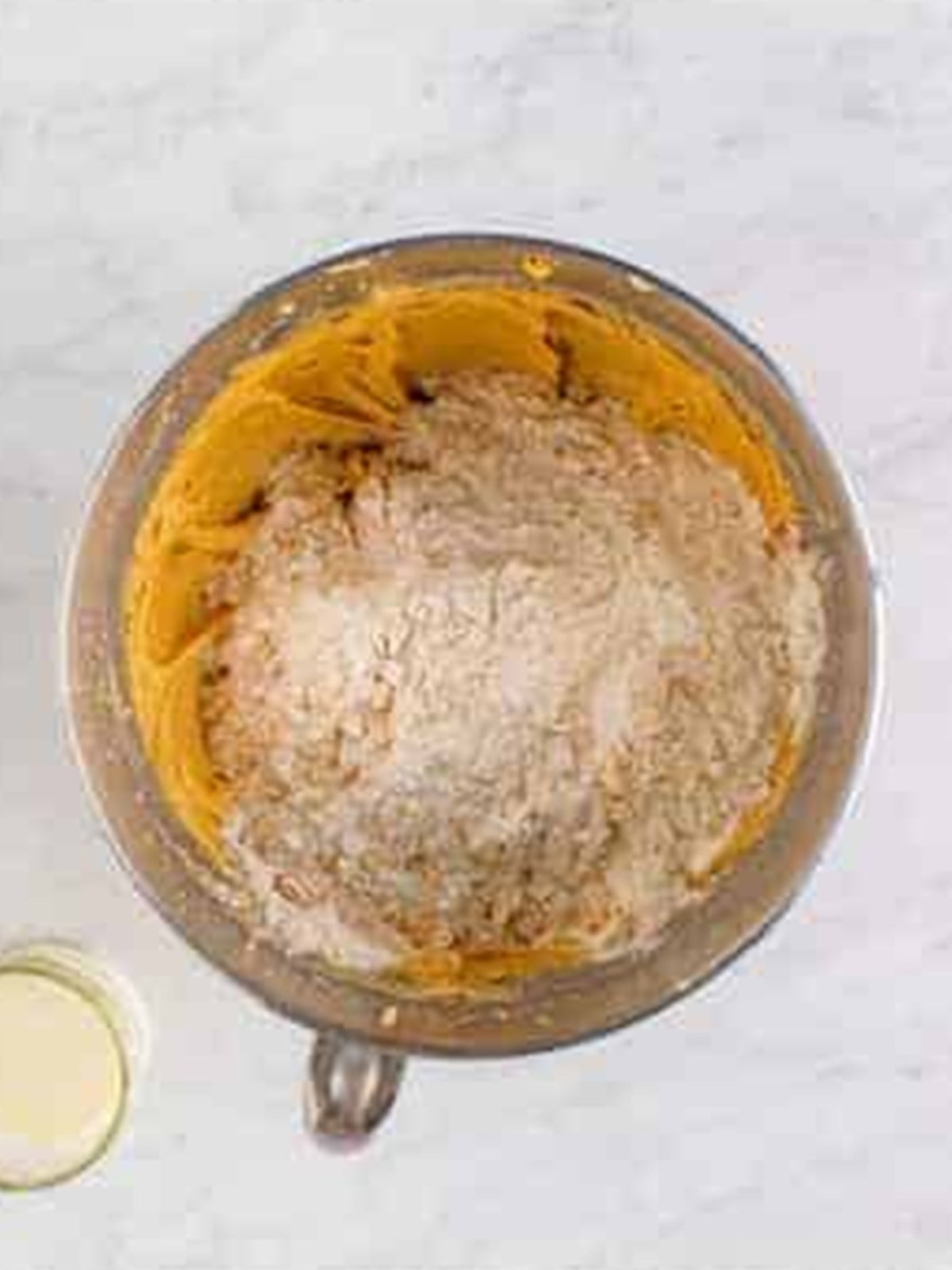 Oats and flour added to the peanut butter dough in the mixer bowl.