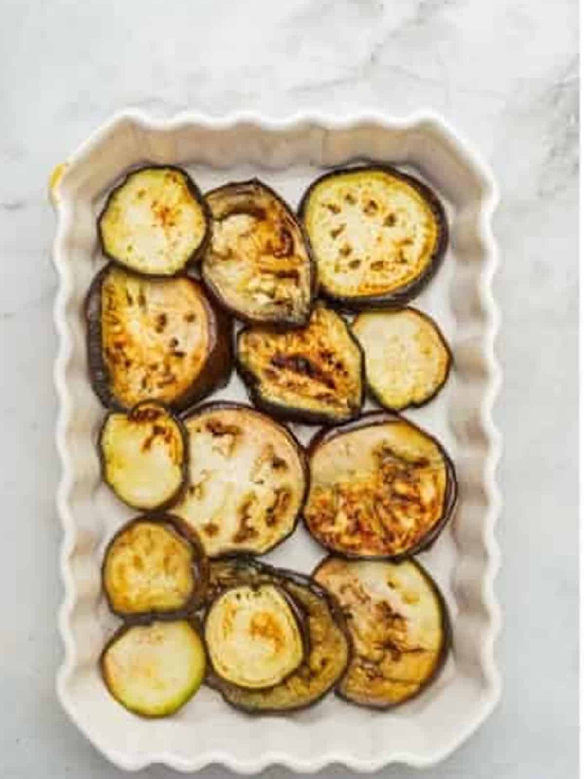 A layer of grilled eggplant slices in a baking dish for moussaka.