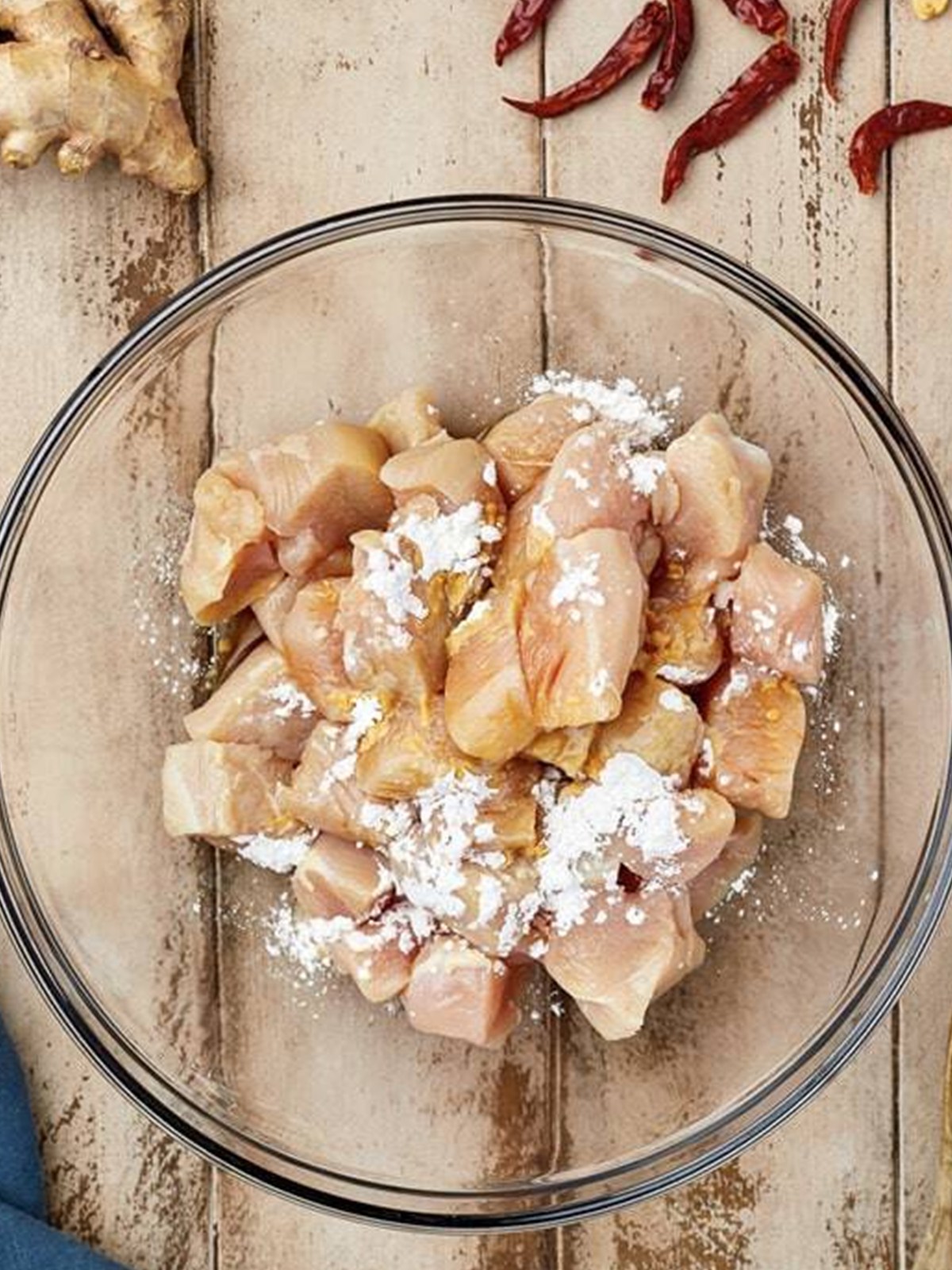 Diced chicken tossed with cornstarch and soy sauce in a glass bowl.