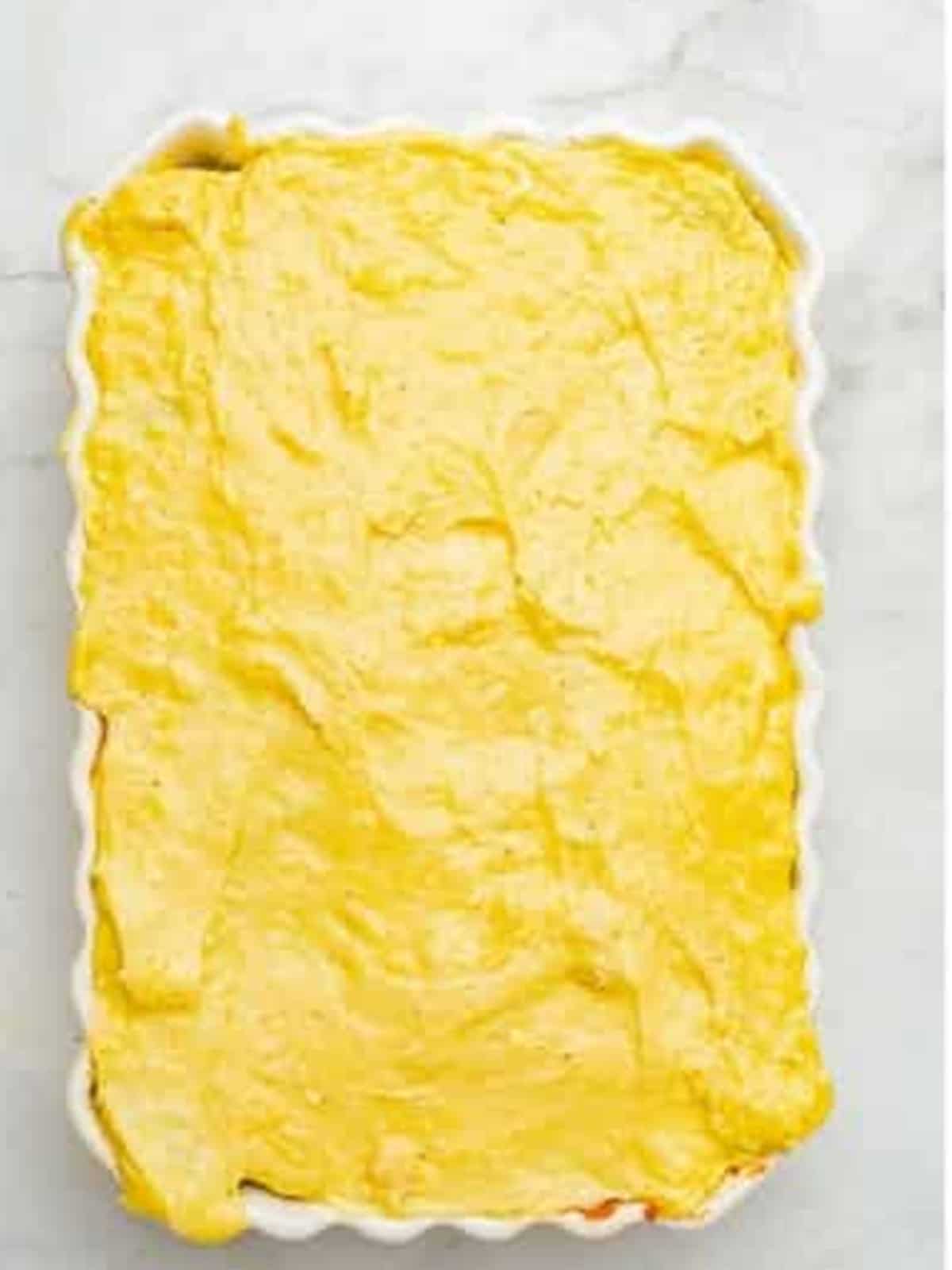 Creamy bechamel sauce spread over the moussaka layers.