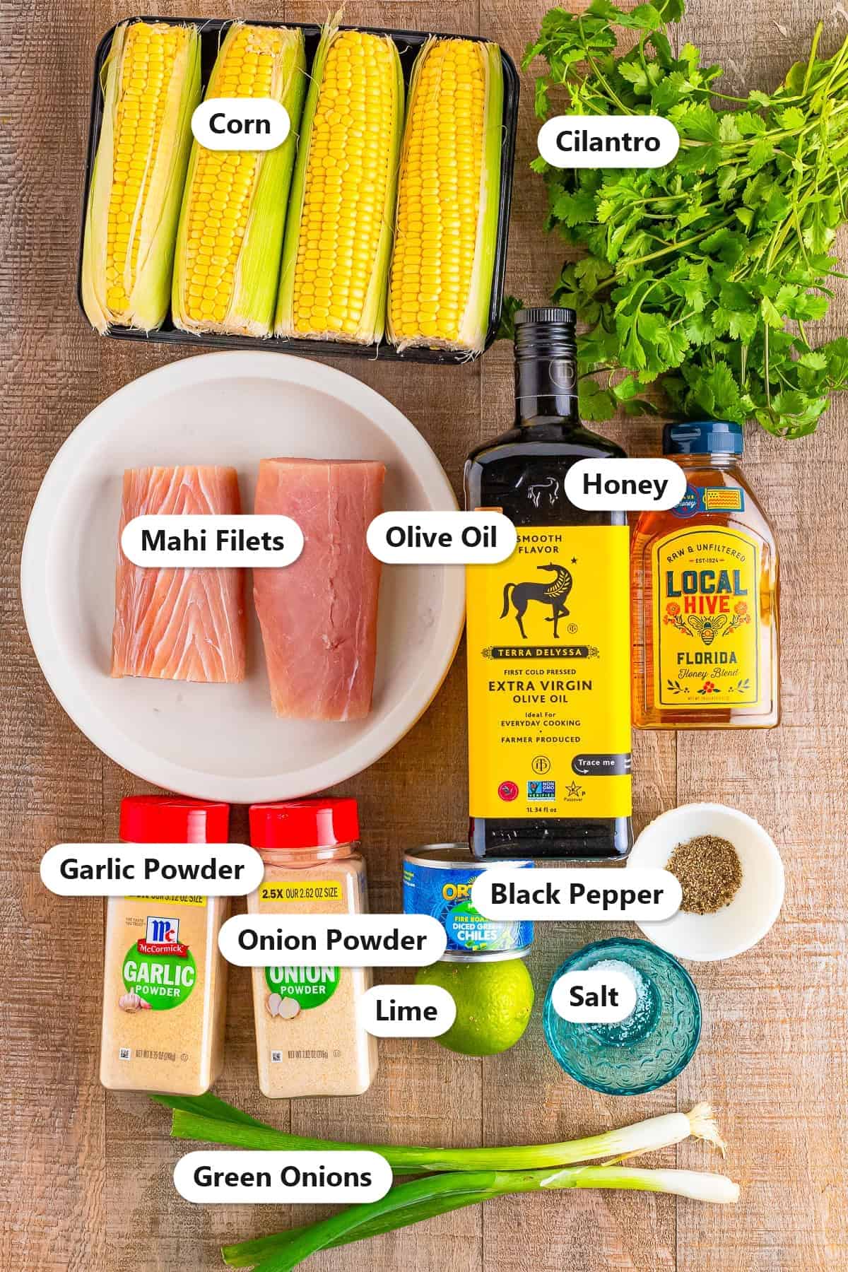 Labeled mahi mahi fish tacos ingredients including mahi filets, lime, cilantro, olive oil, corn, and spices.