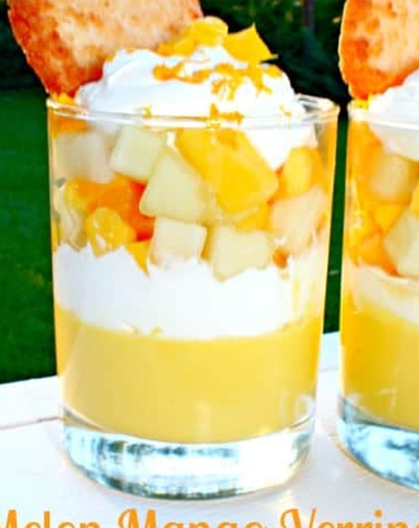 A layered mango dessert verrine showing the mango cream, whipped cream, and fresh fruit layers in a glass.