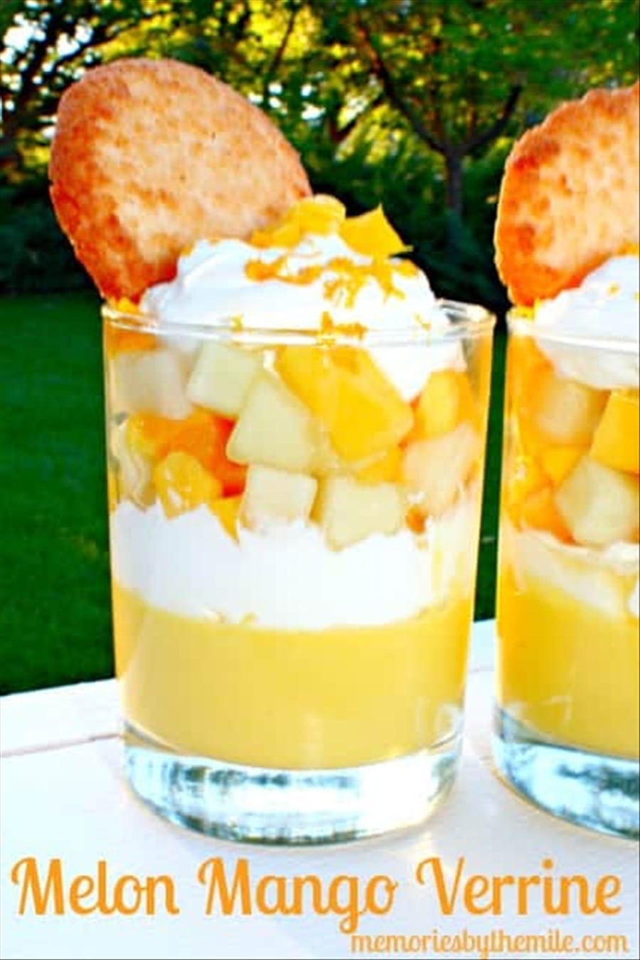 An easy mango dessert layered in glasses, also known as a melon mango verrine, topped with whipped cream and a cookie.