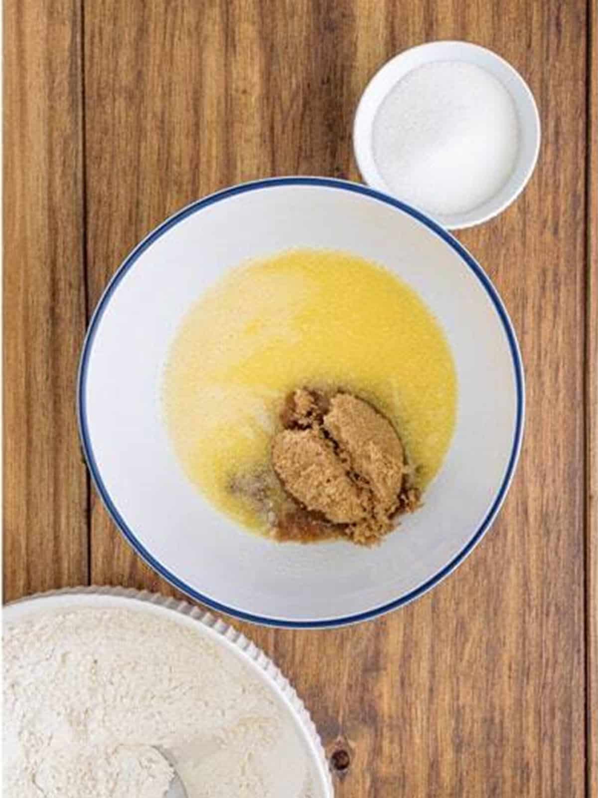 Melted butter and brown sugar added to a white mixing bowl.