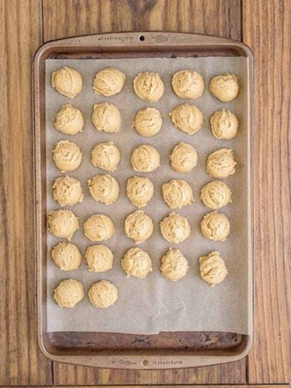 Scooped maple cookie dough portions on a parchment-lined sheet tray ready to chill.