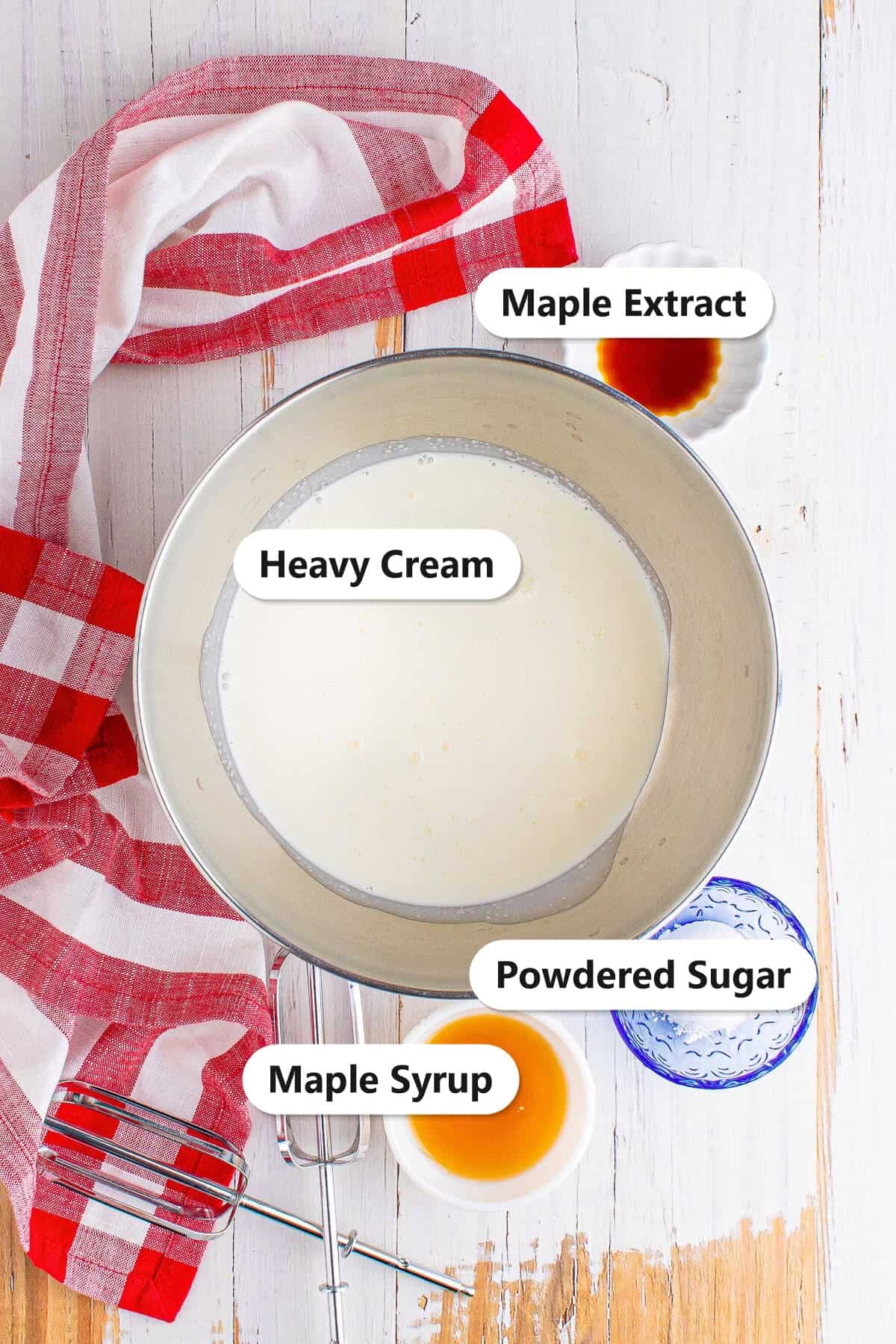 Labeled ingredients to make maple whipped cream including heavy cream, maple syrup, powdered sugar, and maple extract.